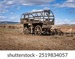 Image of a historic frontier covered wagon with wooden wheels on the scenic landscape in Wyoming, USA