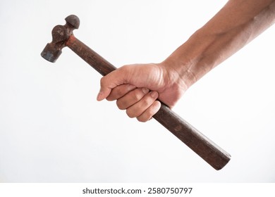 Image of a human hand holding a hammer with a wooden handle. Portrays themes of labor, tools, and craftsmanship. Captures the essence of manual work and vintage tools.