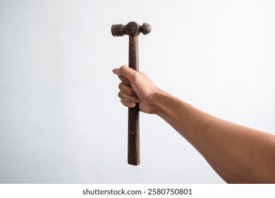 Image of a human hand holding a hammer with a wooden handle. Portrays themes of labor, tools, and craftsmanship. Captures the essence of manual work and vintage tools.