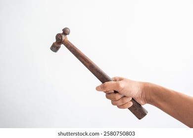 Image of a human hand holding a hammer with a wooden handle. Portrays themes of labor, tools, and craftsmanship. Captures the essence of manual work and vintage tools.
