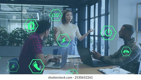 Image of icon in hexagons over diverse woman explaining strategy to coworkers in office. Digital composite, multiple exposure, carbon dioxide, discussion, planning and teamwork concept. - Powered by Shutterstock