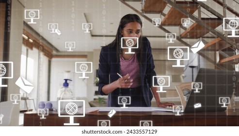 Image of icons and data processing over biracial businesswoman working in office. Global digital interface, cloud computing and data processing concept digitally generated image. - Powered by Shutterstock - Get 15% off with code: PIKWIZARD15
