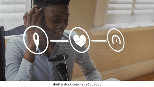 Image of icons and data processing over african american businesswoman talking in office. Global business, finance, computing and data processing concept digitally generated image.