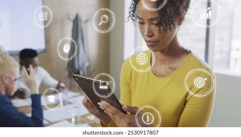 Image of icons and data processing over biracial businesswoman in office. Global business, finances, computing and data processing concept digitally generated image. - Powered by Shutterstock