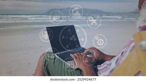 Image of icons over senior african american man using laptop on sunny beach. healthy and active beach holiday concept digitally generated image. - Powered by Shutterstock