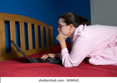 Image illustrating an old cliche: burning the midnight oil. Posture says she is tired but still concentrating on work. She could be a grad student or young aspiring professional.