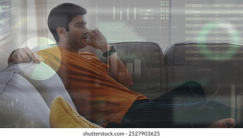 Image of infographic interface over biracial man sitting on sofa and talking on smartphone. Digital composite, multiple exposure, report, business, global and technology concept. - Powered by Shutterstock