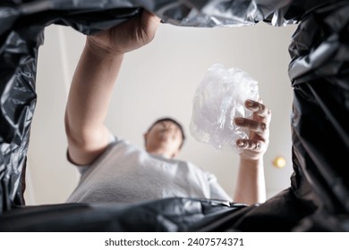 Image from inside black recycling bag of man throwing empty plastic bottle in recycling bin Home recycle eco green zero concept 