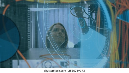 Image of interface with data processing over caucasian female engineer working at server room. Computer interface and business data storage technology concept