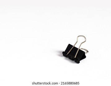 An image isolated binder clip black color stationery paper for office paperclip on the white background with copy space for text.