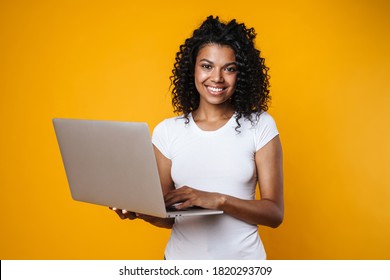 Image Of Joyful African American Woman Smiling And Using Laptop Isolated Over Yellow Background