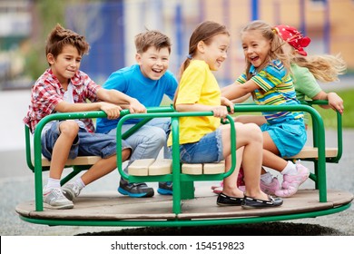 Image of joyful friends having fun on carousel outdoors 