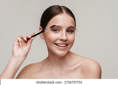 Image Of Joyful Young Shirtless Woman Using Eyebrows Brush And Smiling Isolated Over Grey Background