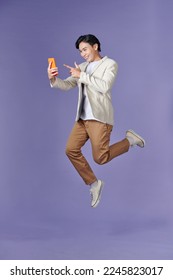 image of jumping up asian man holding smartphone in hand - Shutterstock ID 2245823017