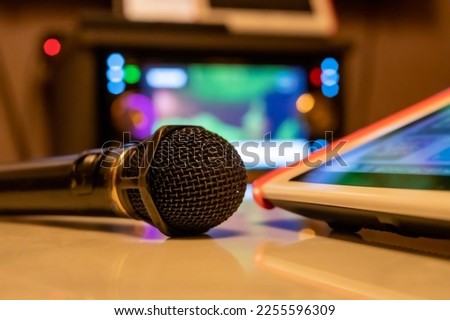 Image of a karaoke microphone and remote control on a table