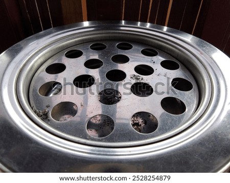 image of a large ashtray, small circle motif for disposing of cigarette ash

