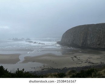 Image of large rock formation and empty beach during a rainy, overcast day in Oregon. - Powered by Shutterstock