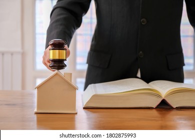 Image of lawyer holding a auction hammer on model house. Concept of the law is to buy or sell houses and land, mortgage.