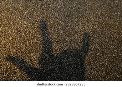 The image of the left hand's shadow was deliberately photographed against a unique textured wall background, the photo was taken in the morning so the image is slightly golden yellow