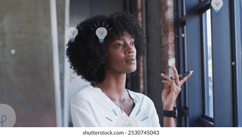 Image of light bulb icons over african american businesswoman in office. Global social media, networks, digital interface and data processing concept digitally generated image. - Powered by Shutterstock