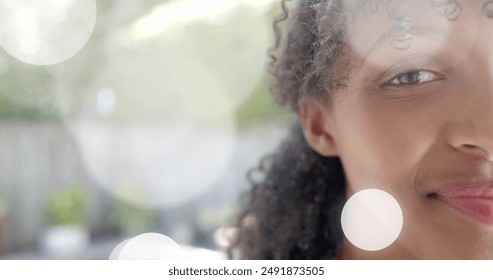 Image of light spots over half portrait of happy biracial teenage girl smiling in garden. Youth, wellbeing and lifestyle, digitally generated image. - Powered by Shutterstock