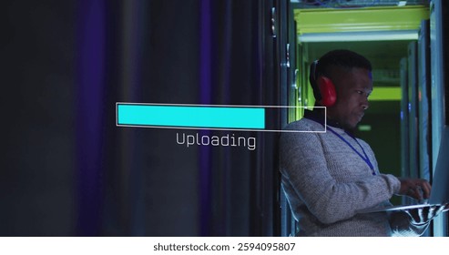 Image of loading bar over african american man working in server room. Global technology and digital interface concept digitally generated image.