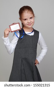 Image Of Lovely Little Girl In A School Uniform With A Name Tag On A Gray Background/Little Girl With A Blank Name Tag