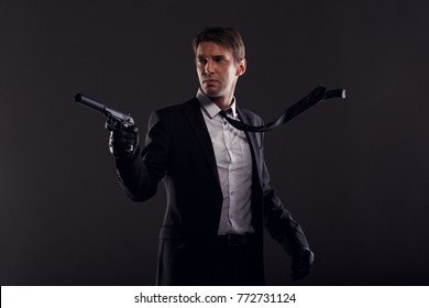 Image of mafia man with emerging tie in leather gloves with gun