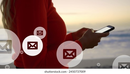 Image of mail icons over midsection of biracial woman using smartphone at beach. global connections, social media, technology and digital interface concept digitally generated image. - Powered by Shutterstock