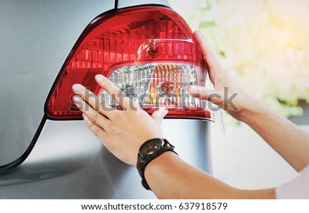 Image of a man checking his tail light before traveling.