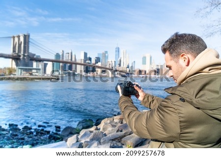IMAGE OF A MAN FILMING THE SKYLINE OF NEW YORK CITY. TRAVEL AND SUNNY DAY CONCEPT.