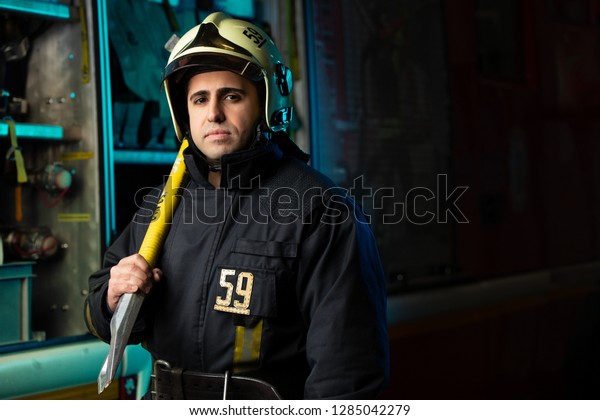 Image of man\
firefighter with pick near fire\
truck