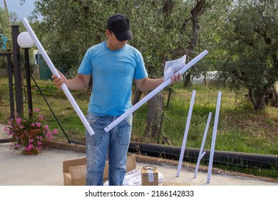 Image Of A Man Holding Two Pipes And An Instruction Booklet For Assembling An Above Ground Pool.
