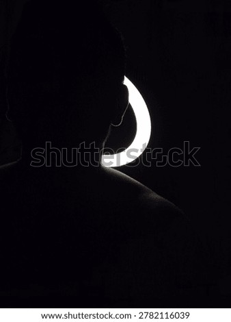Image of a man with a ring light in the background, Male physique and fitness, Muscles and Confidence Concept, Male Physique and health. Silhouette of a man in studio setting, Male Selfcare and life.