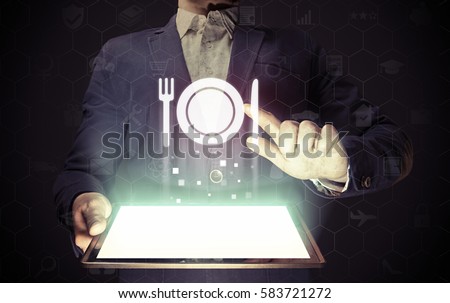 Image of a man with tablet in his hands and food restaurant icon. He looking menus, ordering food delivery, rate restaurant with using online services.