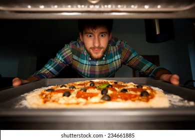 Image Of Man Taking Pizza From Oven