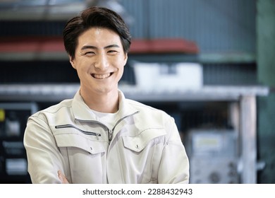 Image of a man in work clothes, arms folded, looking at the camera	 - Powered by Shutterstock