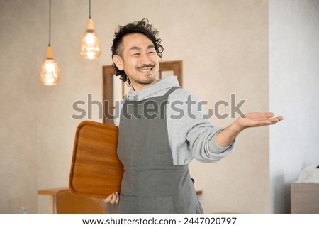 The image of a manager, owner or proprietor of a fashionable cafe or restaurant. A scene of a middle-aged Japanese man serving customers. The customer service industry.