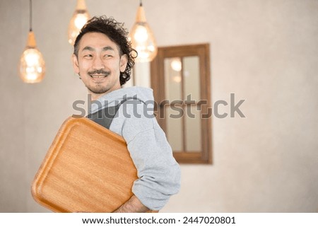 The image of a manager, owner, or proprietor of a fashionable cafe or restaurant. Close-up of the upper half of an image of a middle-aged Japanese man working. The hospitality industry.