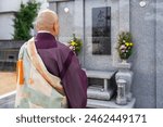 Image material of a monk praying at a Buddhist altar.On the tombstone is written in kanji ``Eternal Memorial Service.