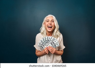 Image Of Mature Happy Old Woman Standing Isolated Over Dark Blue Background Wall Looking Camera Holding Money.