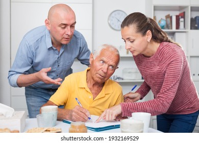 Image of mature man at table in home kitchen filling up documents with family - Shutterstock ID 1932169529