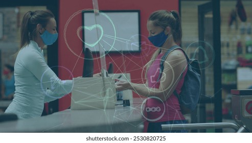 Image of media icons over caucasian woman with face mask disinfecting hands. social media and communication interface during covid 19 pandemic concept digitally generated image. - Powered by Shutterstock