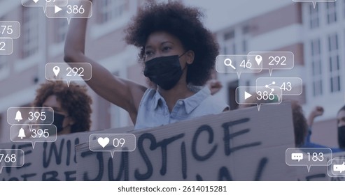 Image of media icons over diverse people with face masks raising hands and protesting. social media and communication interface during pandemic concept digitally generated image.