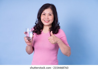 Image Of Middle Aged Asian Woman Drinking Water On Blue Background