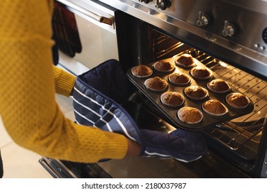 Image of midsection of african american senior woman taking out cupcakes from oven. Lifestyle, baking and spending time at home concept. - Powered by Shutterstock