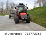 Image mini-tractor with trailer standing on the track in the park.