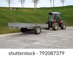 Image mini-tractor with trailer standing on the track in the park.