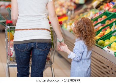 Image Of A Mother Holding Her Kids Hand Inside The Food Department In A Supermarket.