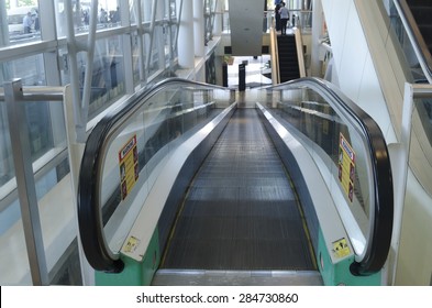 Image Of A Moving Walkway Or Inclined Travellator At An Airport. Nobody Is Using The Moving Walkway At The Time Of Image Taken. Glass Side Rails And Black Rubber Handrails. 